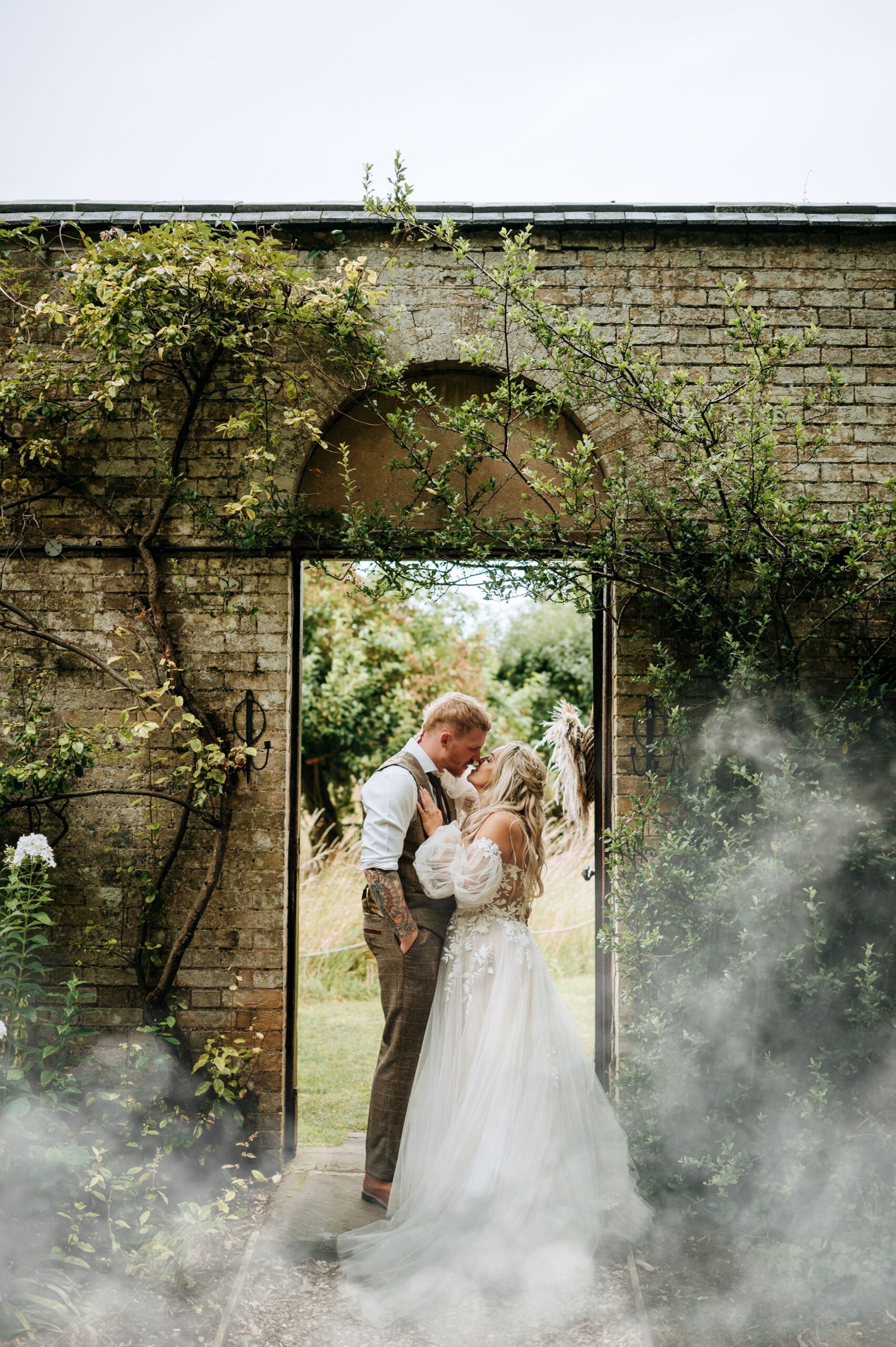 Bride standing beneath floral arch at Scrivelsby wedding venue