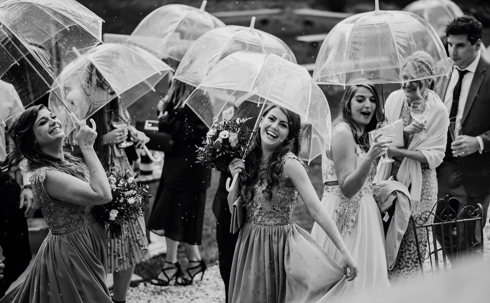 Black and white wedding guests with umbrellas at Hirst Priory