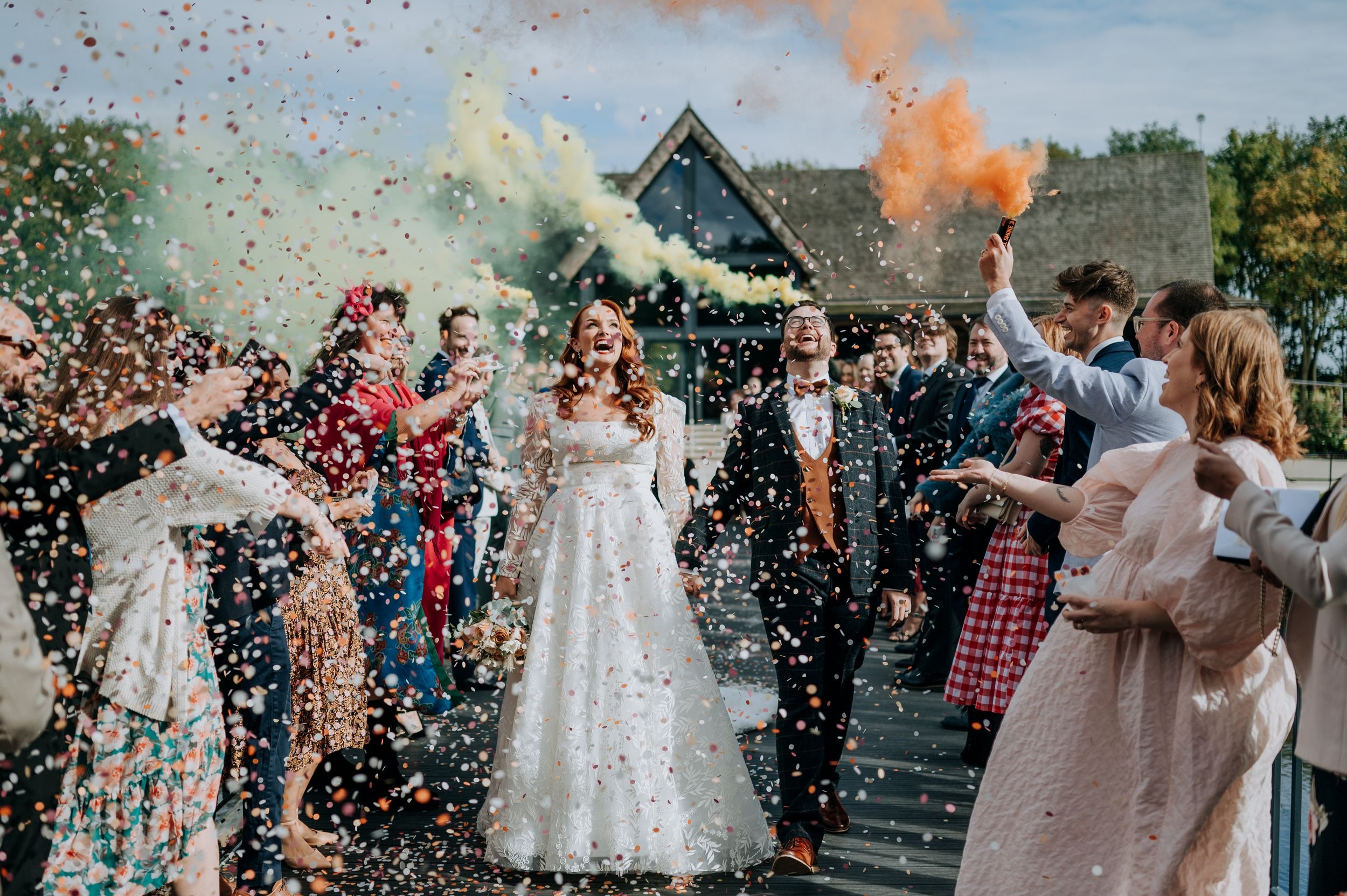Bride and groom walking through confetti at Oaklands wedding venue
