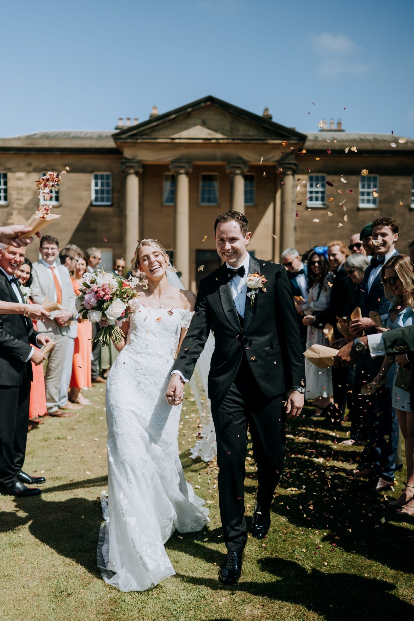 Bride and groom confetti walk outside Rise Hall wedding venue