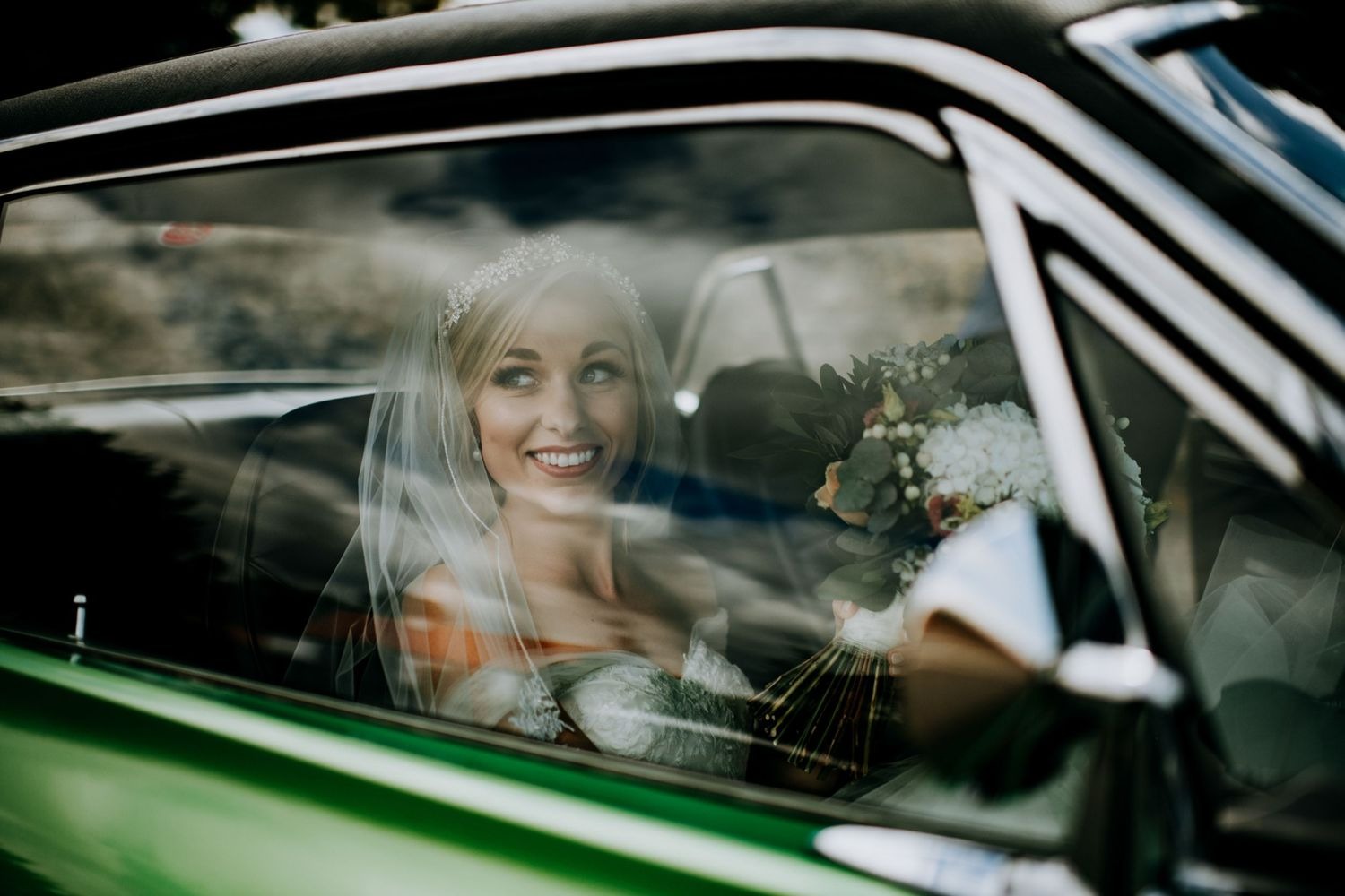Bride smiling from vintage wedding car in Lincolnshire