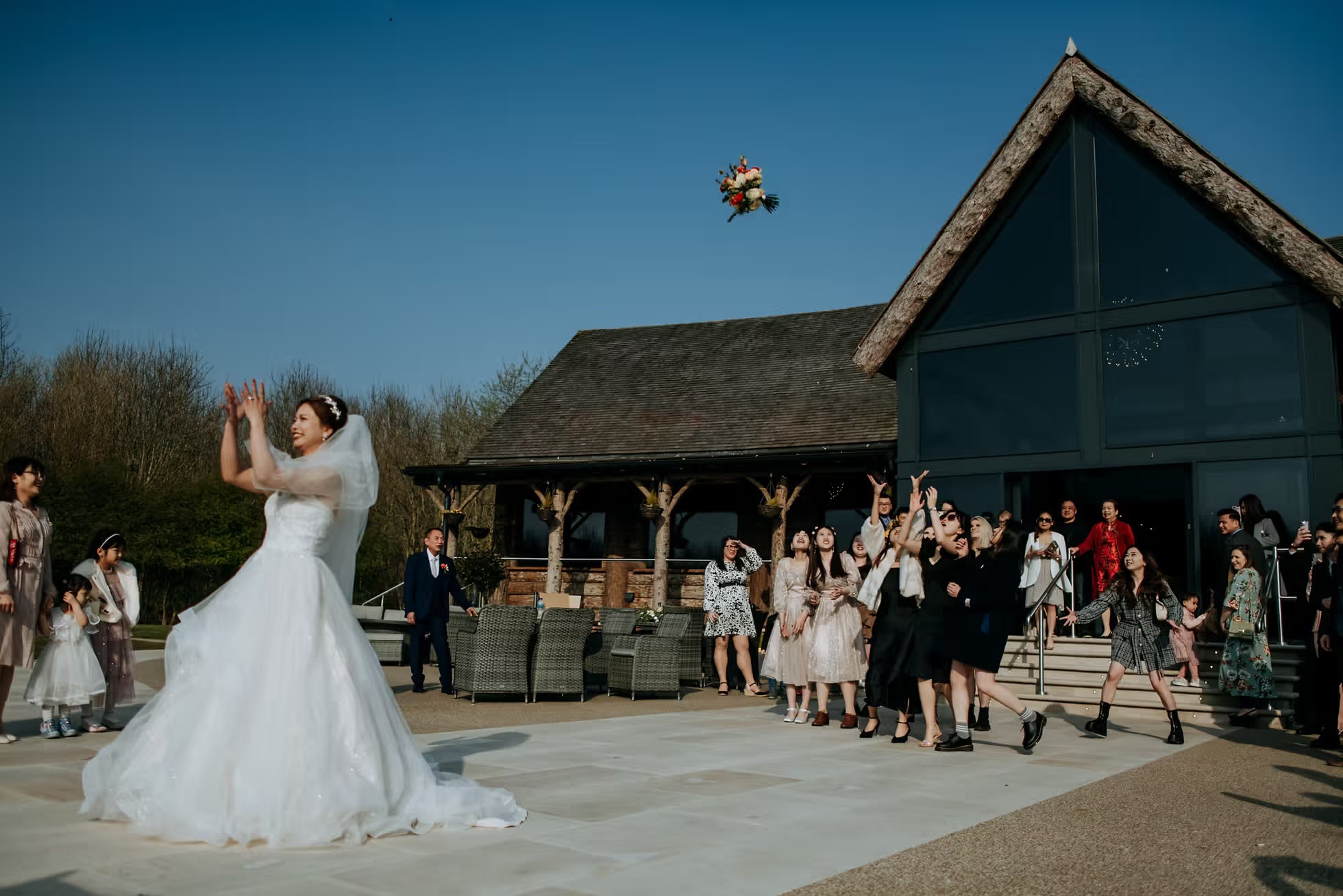 Bride throwing bouquet outside Oaklands wedding venue