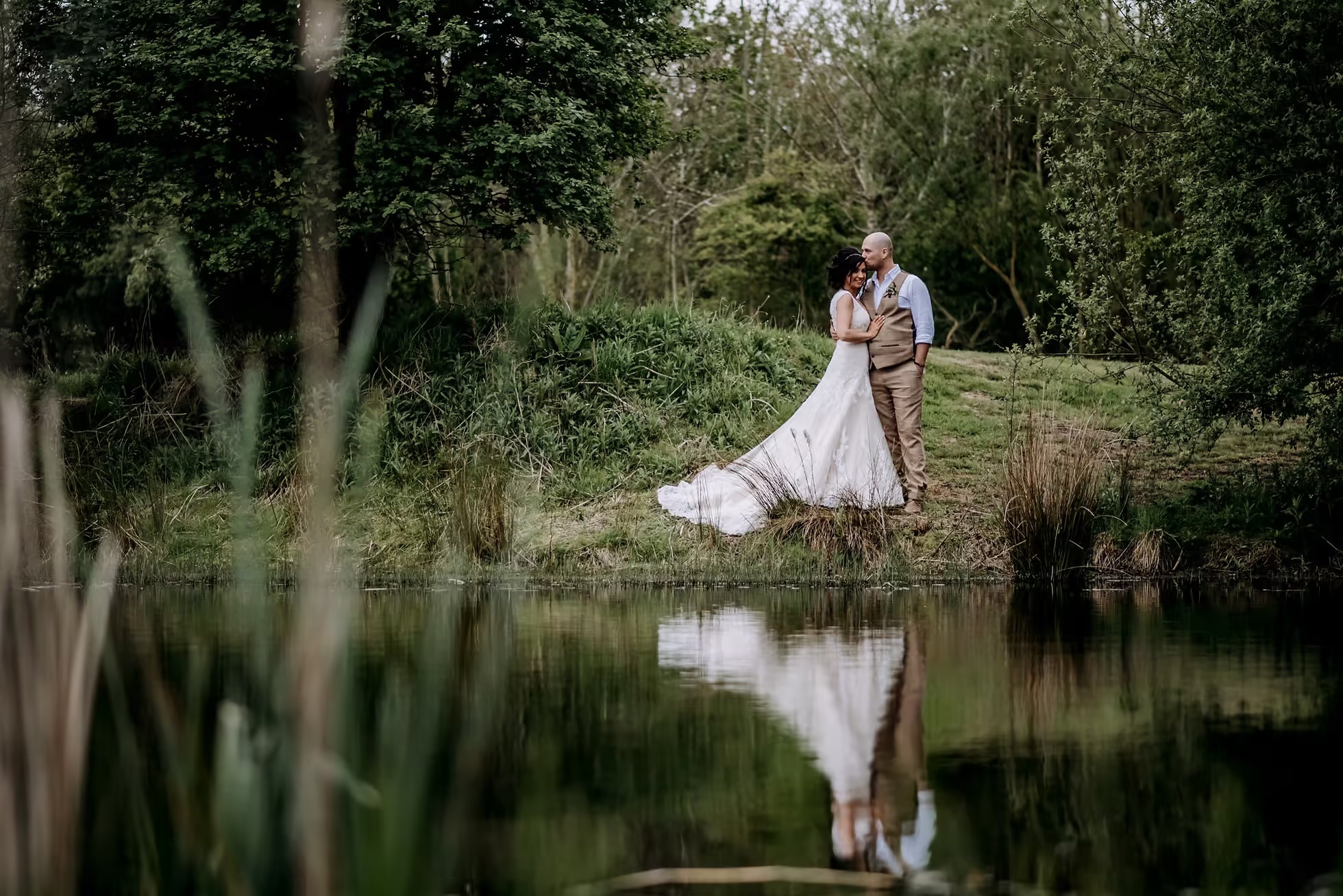 Bride and groom portrait beside lake at Oaklands wedding venue