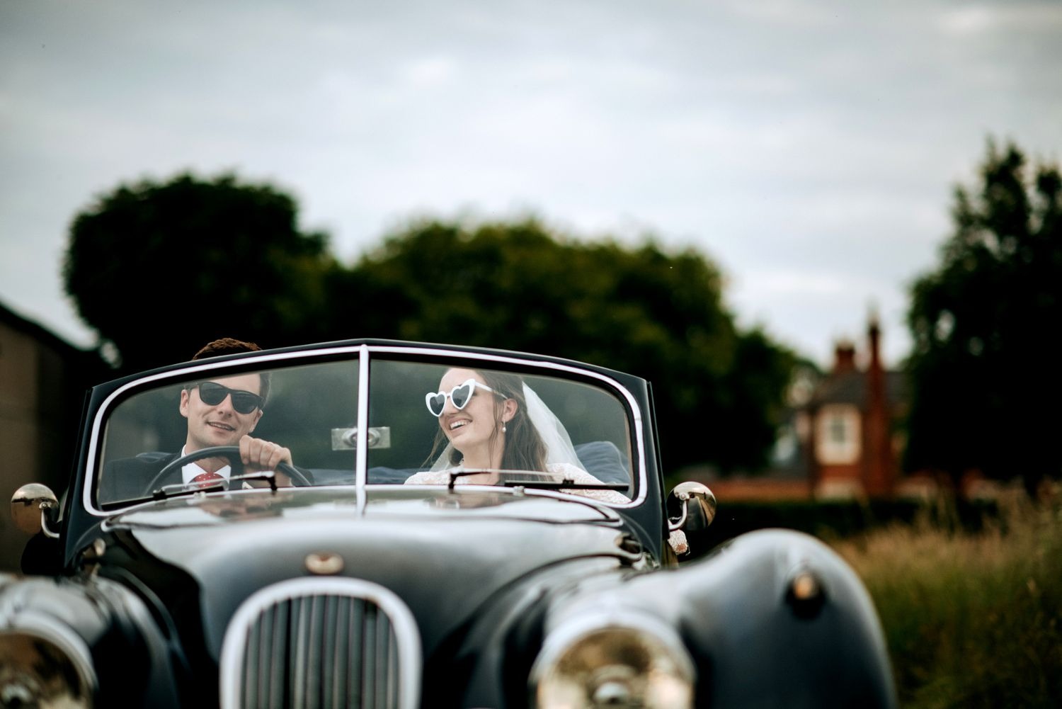 Bride and groom driving vintage wedding car in Lincolnshire