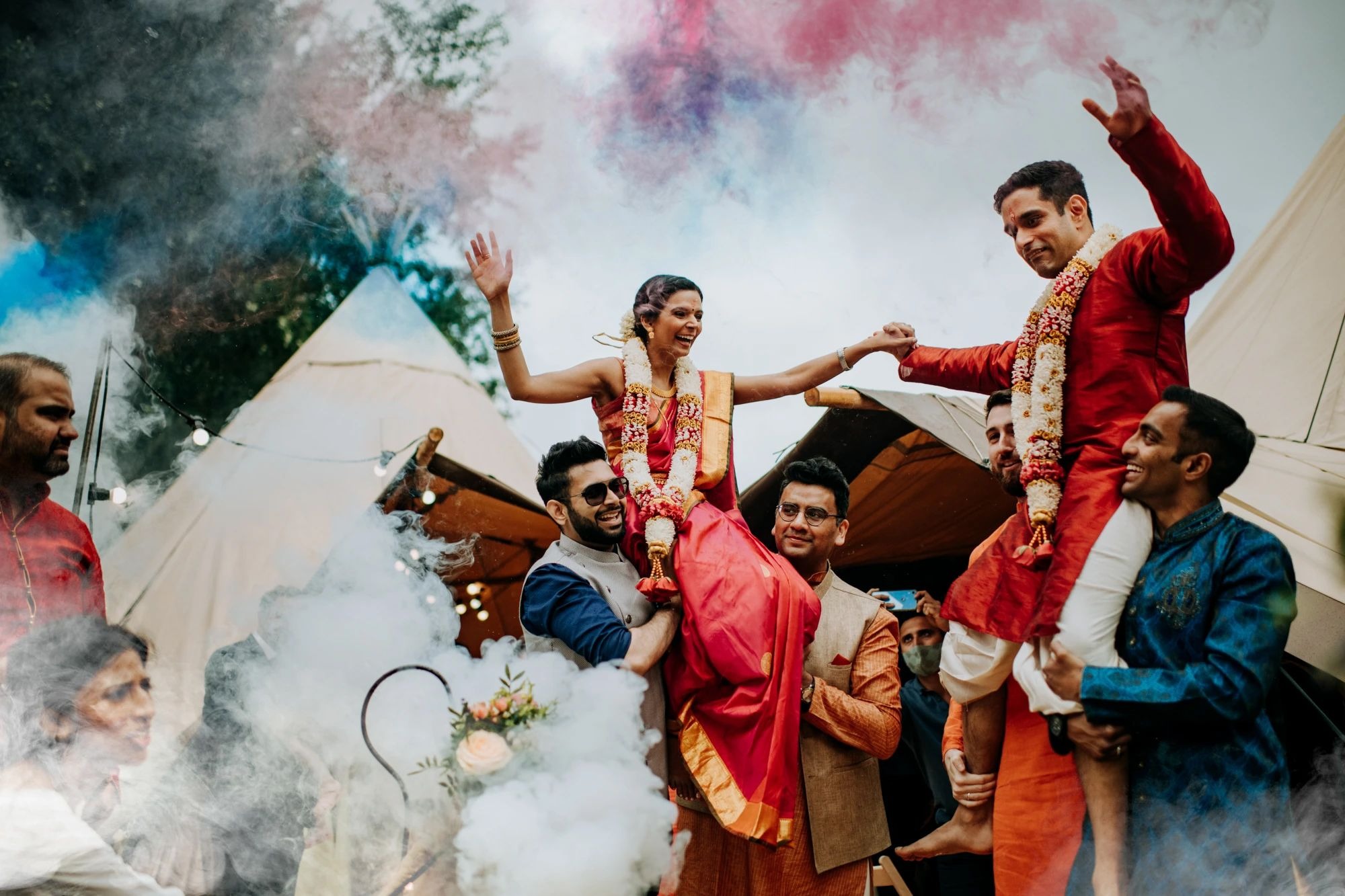 Wedding guests celebrating with colourful smoke bombs at Hirst Priory