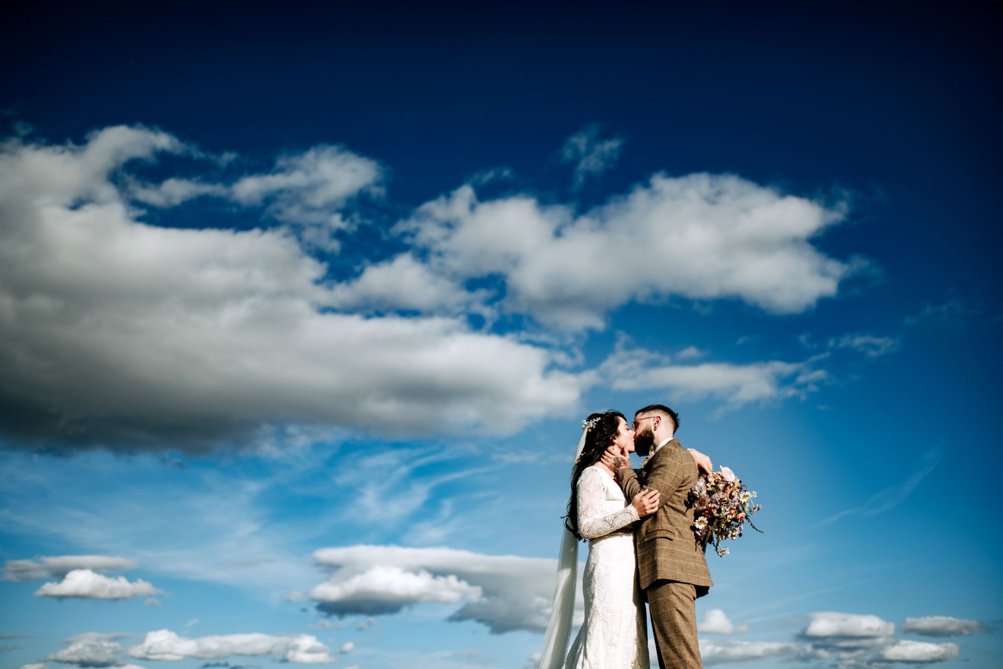 Bride and groom portrait beneath blue sky at Riverlands