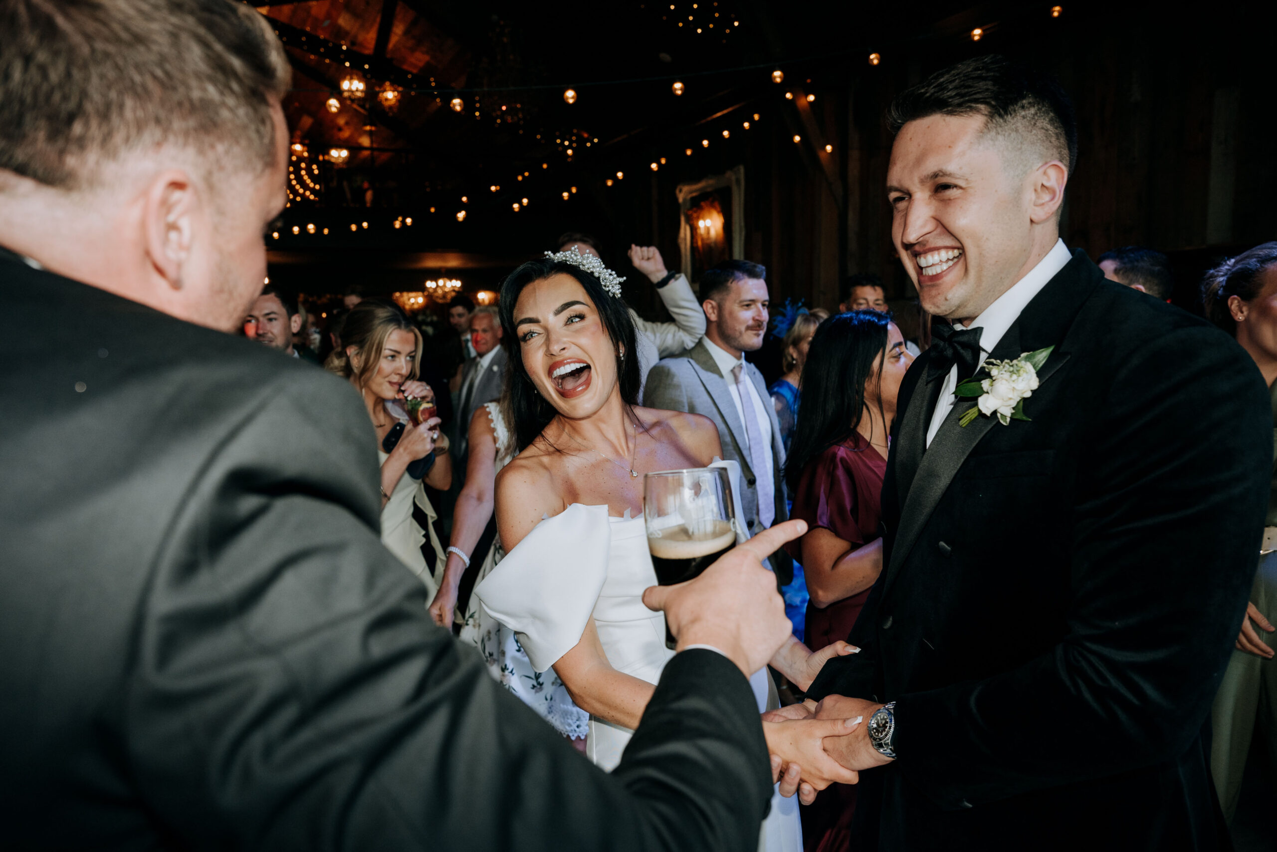 Guest making bride and groom laugh at evening wedding reception at Wharfdale Grange