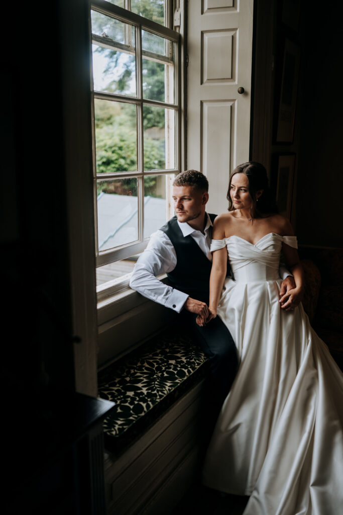 Bride and Groom sat at a window for a portrait photograph at their Washingborough Hall wedding